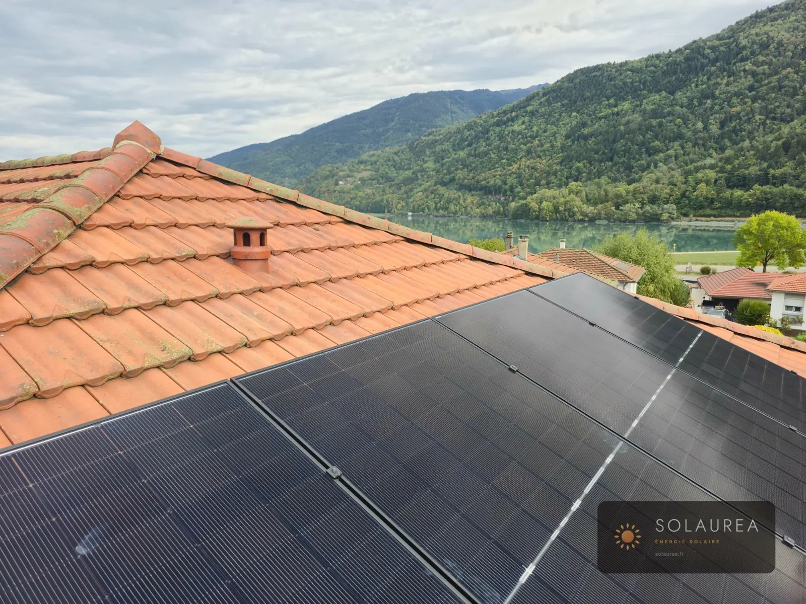 Panneaux solaires sur un toit de tuiles à Crêts en Belledonne, 3 kWc, plan d'eau et versants boisés en arrière-plan